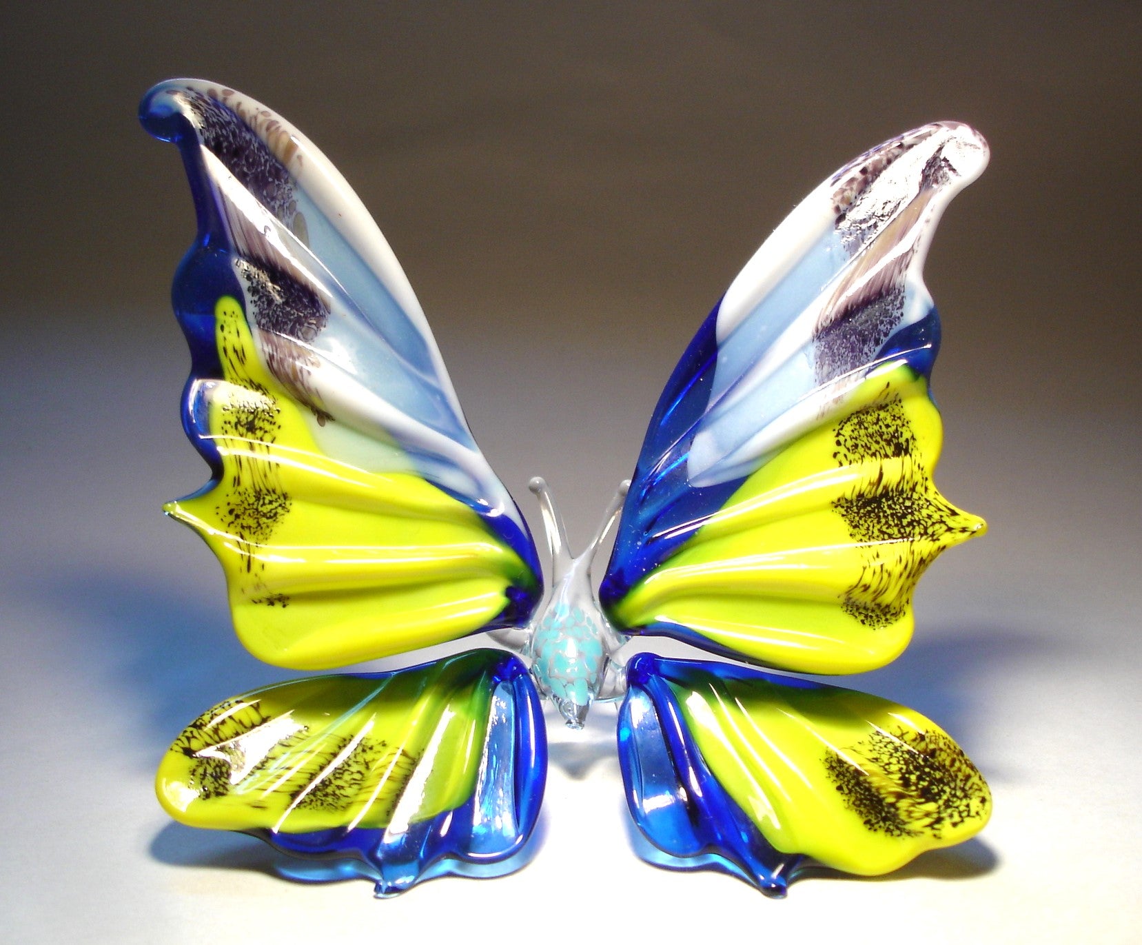 front view of the standing butterfly. It's blue with white and yellow on it's wings