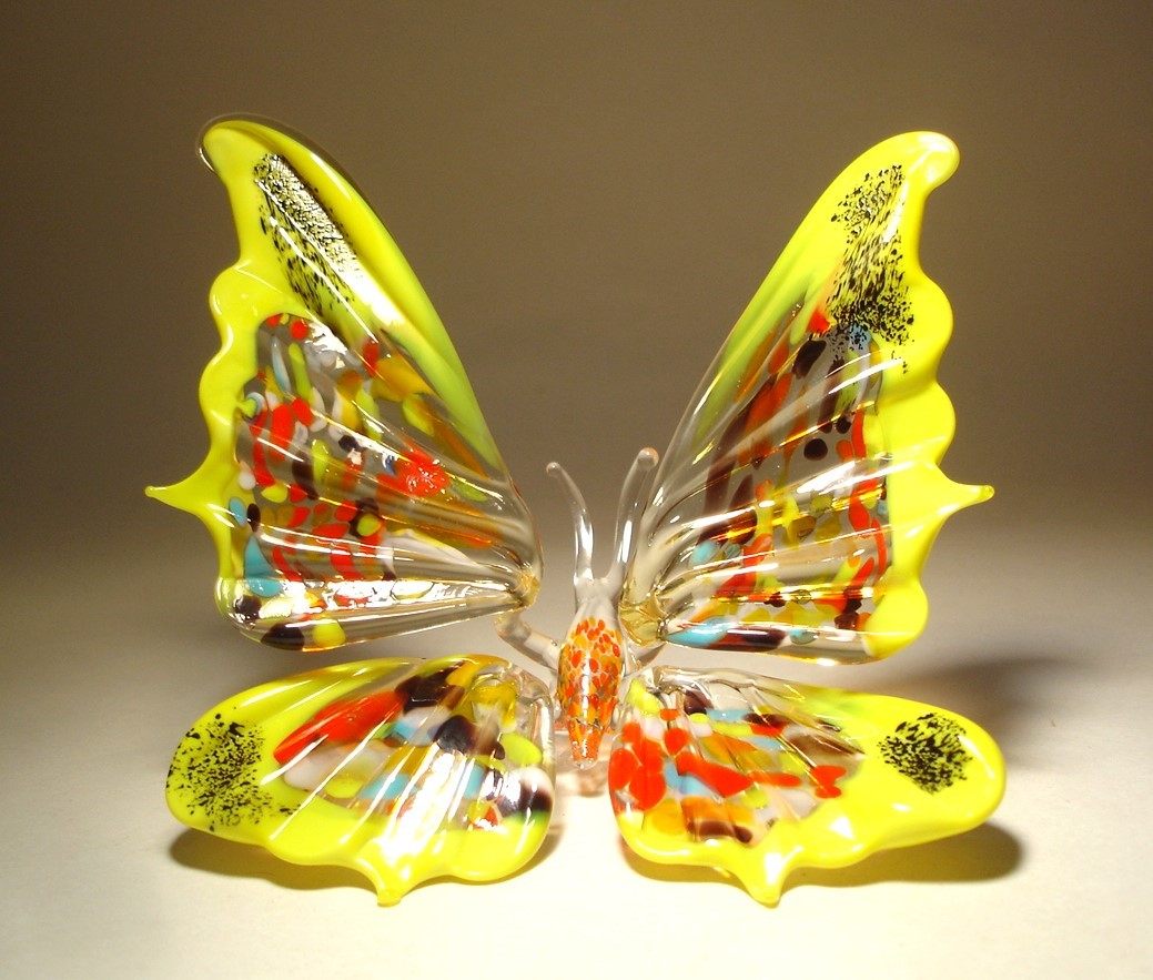 Close-up of a handmade yellow and red glass butterfly figurine with open wings, showcasing its vibrant colors and intricate wing patterns.