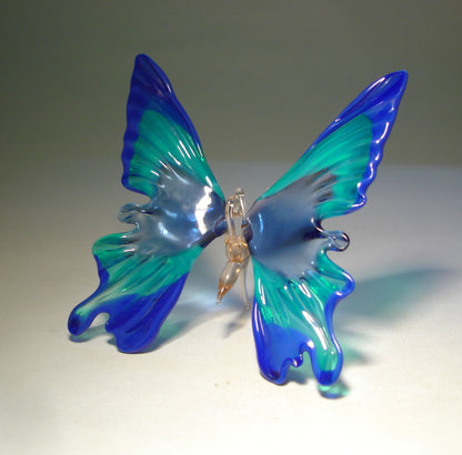 blue glass butterfly ornament, sitting on a surface, focusing on reflective qualities of the glass