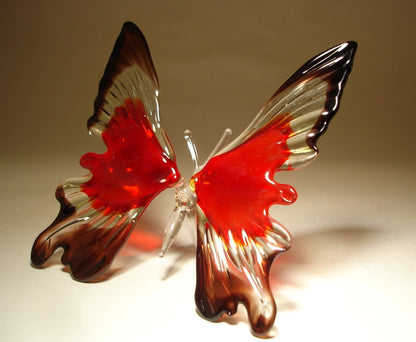 A side view of the red and black glass butterfly ornament, emphasizing the graceful curves of its wings and the contrast between the bold red and deep black.