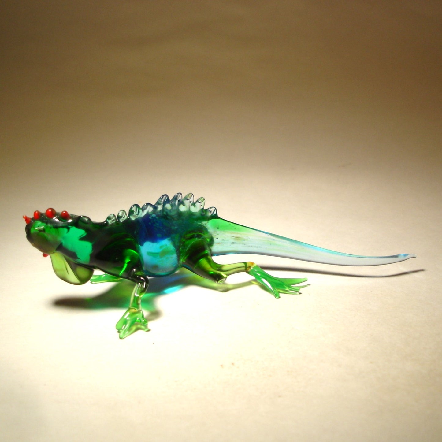 A glass figurine of a Grand Cayman iguana in a blue and green color combination. 