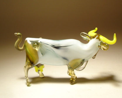 Back side of a white glass cow with yellow horns.