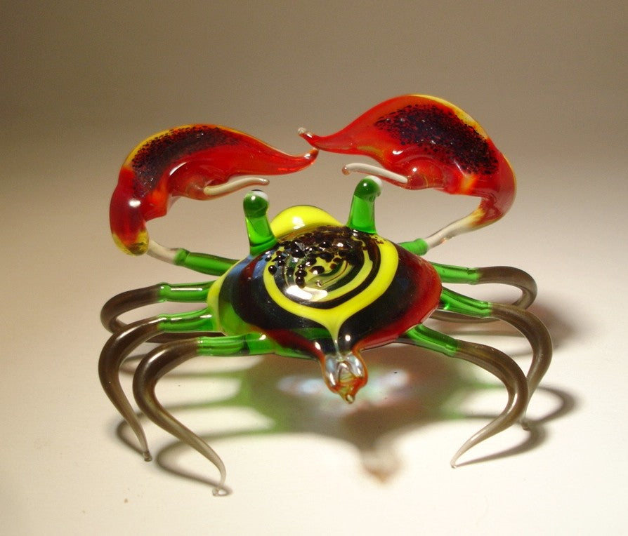 Front view of a glass crab figurine with vibrant red claws, showcasing its detailed colorful shell and legs.