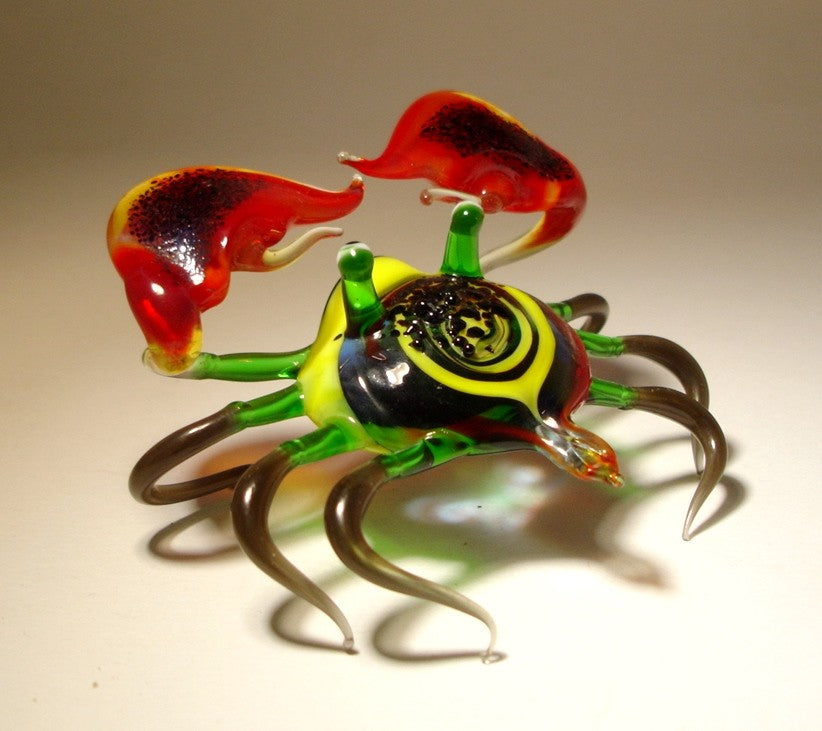 Side view of the glass crab figurine, highlighting the glossy red claws and intricate design of its legs.