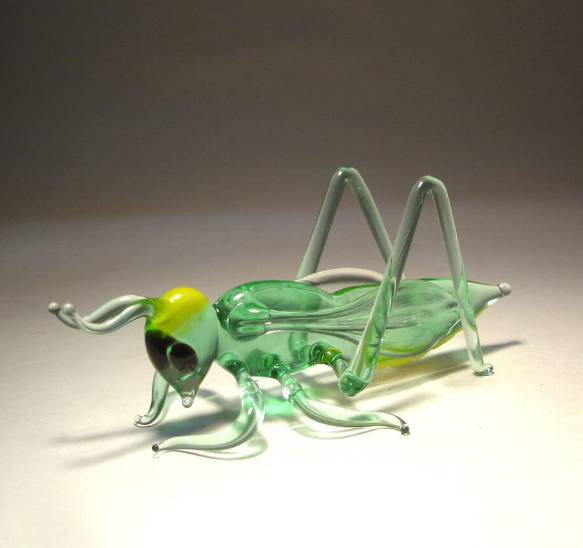 Side view of the glass cricket grasshopper figurine, emphasizing the intricate detailing of its wings and long legs.