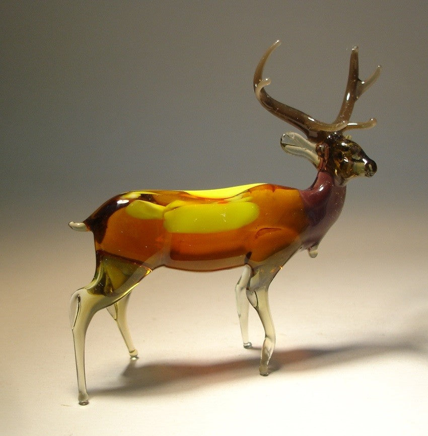 A handcrafted glass elk figurine standing proudly with its large, intricate antlers raised high.