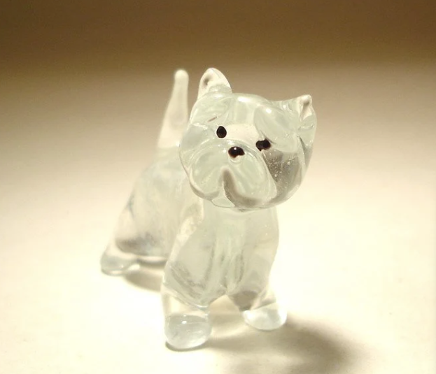 A close-up view of the glass West Highland Terrier figurine highlights its expressive face, with black eyes and nose.