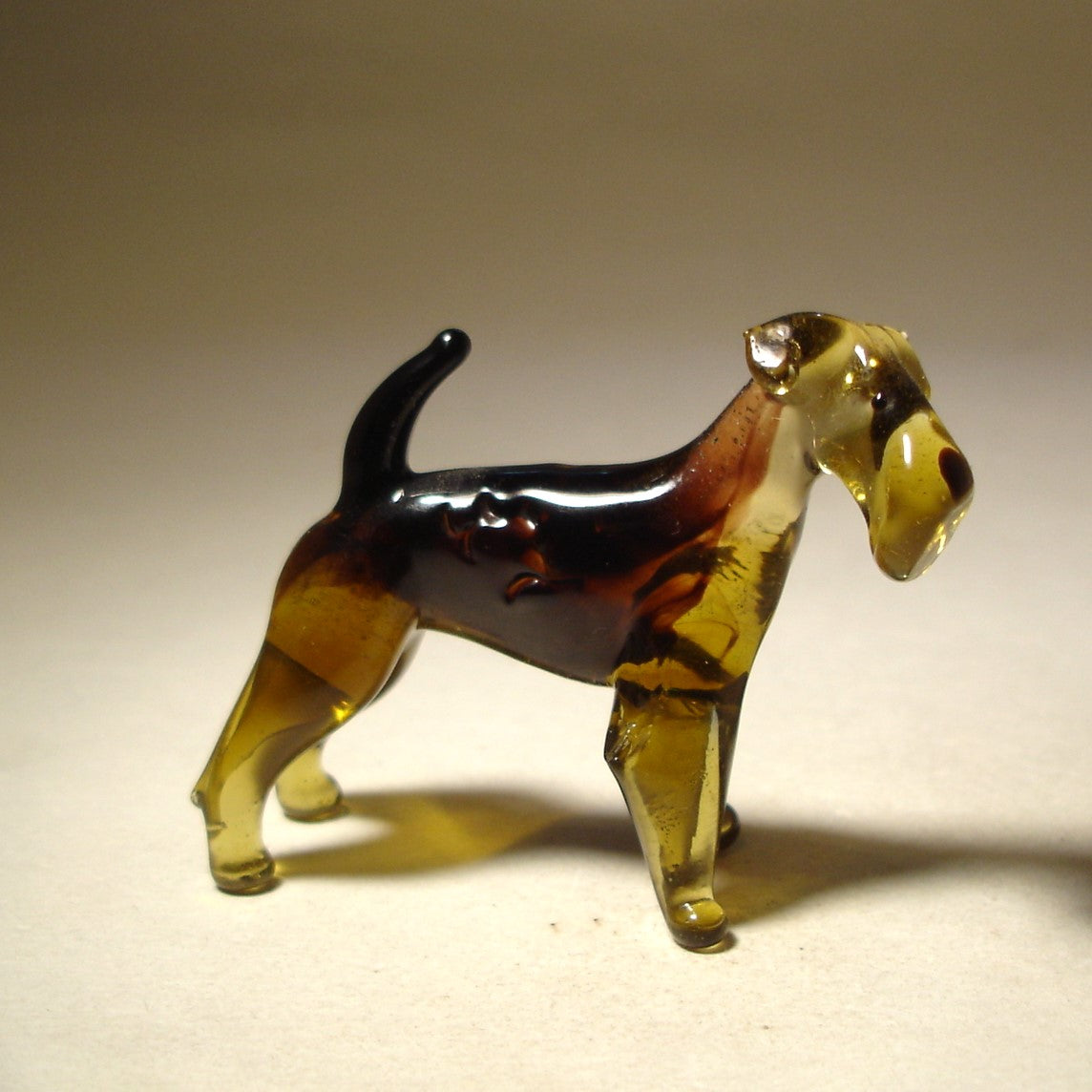 Handcrafted glass Airedale Terrier figurine standing with its tail \ raised, showcasing the dog’s detailed wiry coat and strong stance