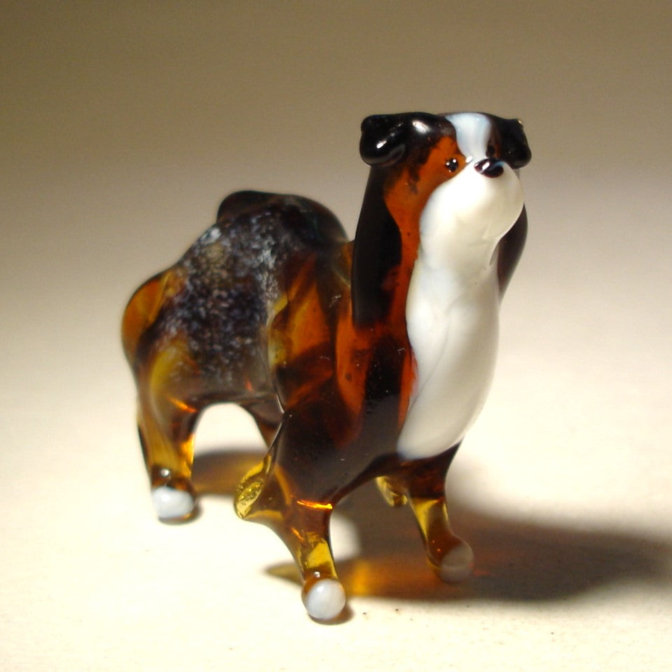 Close-up of the glass Border Collie figurine's face, showing its intelligent eyes and white patch of white fur on its neck.