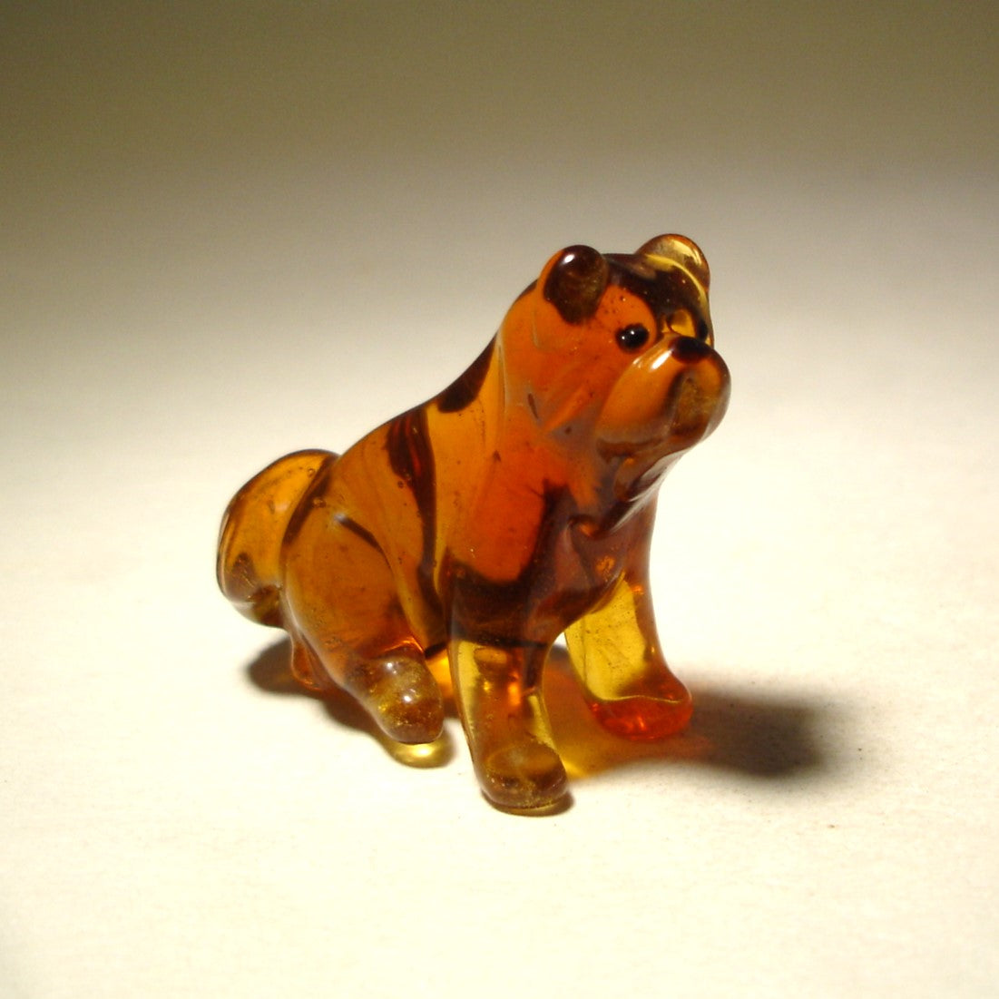 Side view of the glass Chow Chow figurine, highlighting its sturdy build and bushy tail curled over its back.