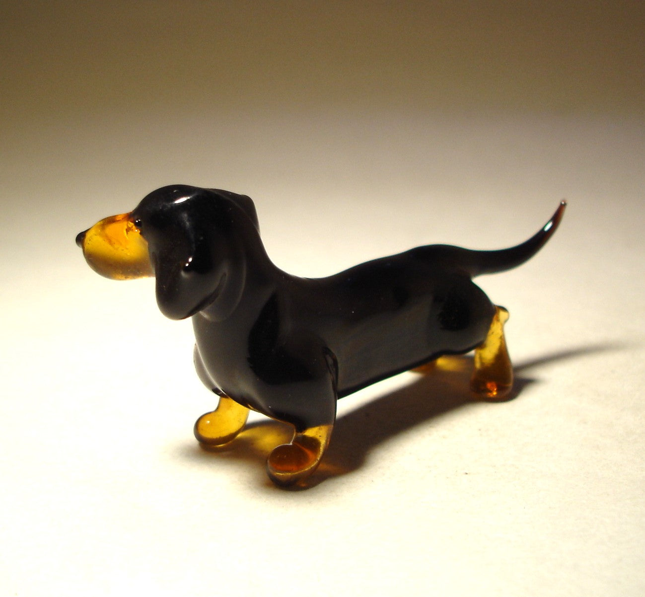 Side view of the glass black Dachshund figurine, highlighting its smooth body and drooping ears.