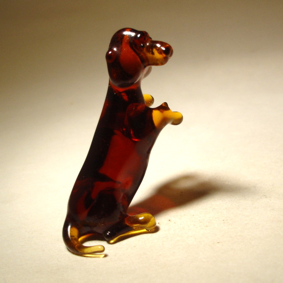 Handmade glass Dachshund figurine in a sitting position, showcasing its long body and short legs