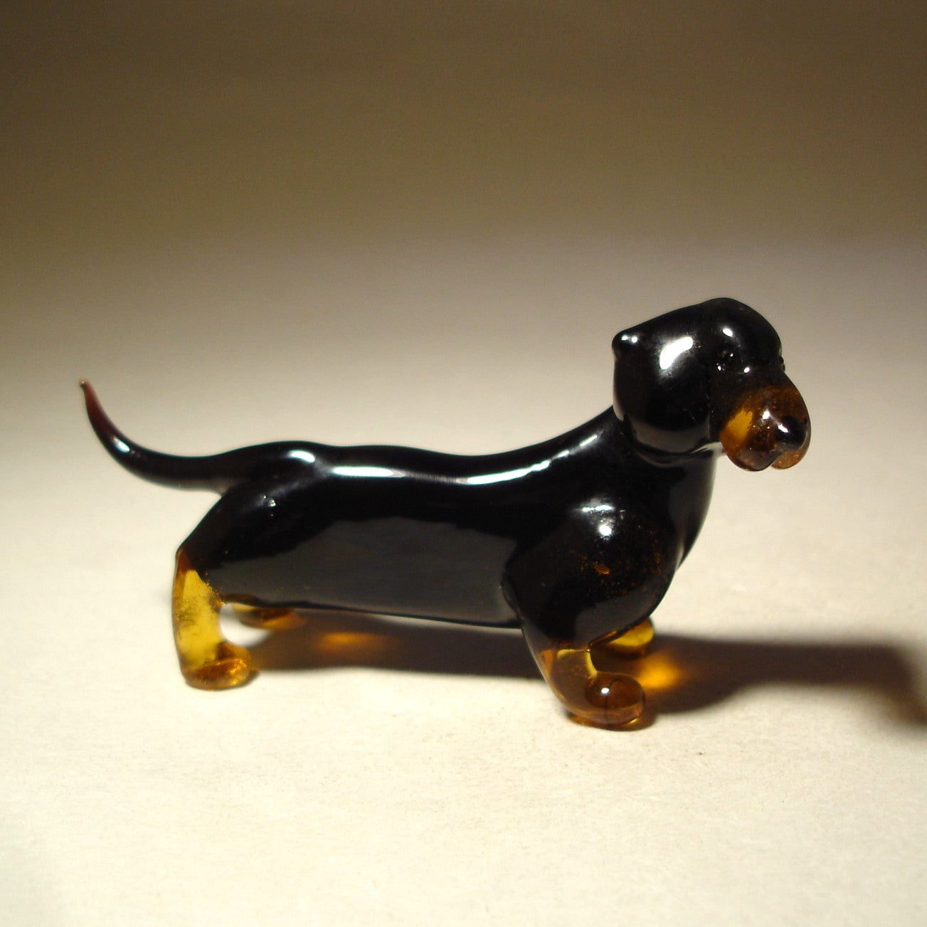 Handmade glass black Dachshund figurine standing with its long body and short brown legs, showcasing the breed’s distinct silhouette.