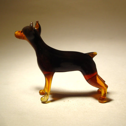 Side view of the glass Doberman figurine, showcasing its pointed ears and strong, muscular stance.