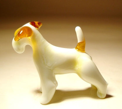 A side view of the glass Fox Terrier dog figurine, emphasizing its athletic stance and white coat with light brown markings.