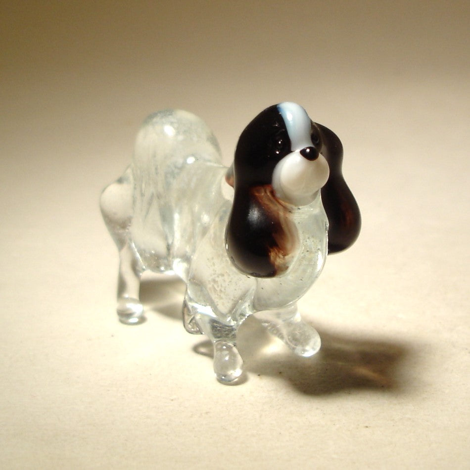 A close-up view of the glass Japanese Chin figurine, highlighting the intricate detailing of its fur and the delicate features of its face.