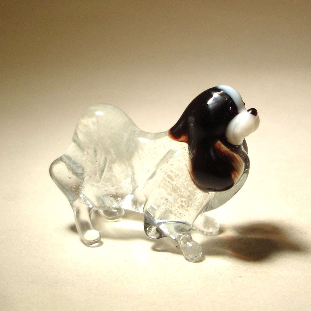 A handcrafted glass Japanese Chin figurine with a glossy finish, showcasing its distinctive long, flowing coat and expressive eyes.