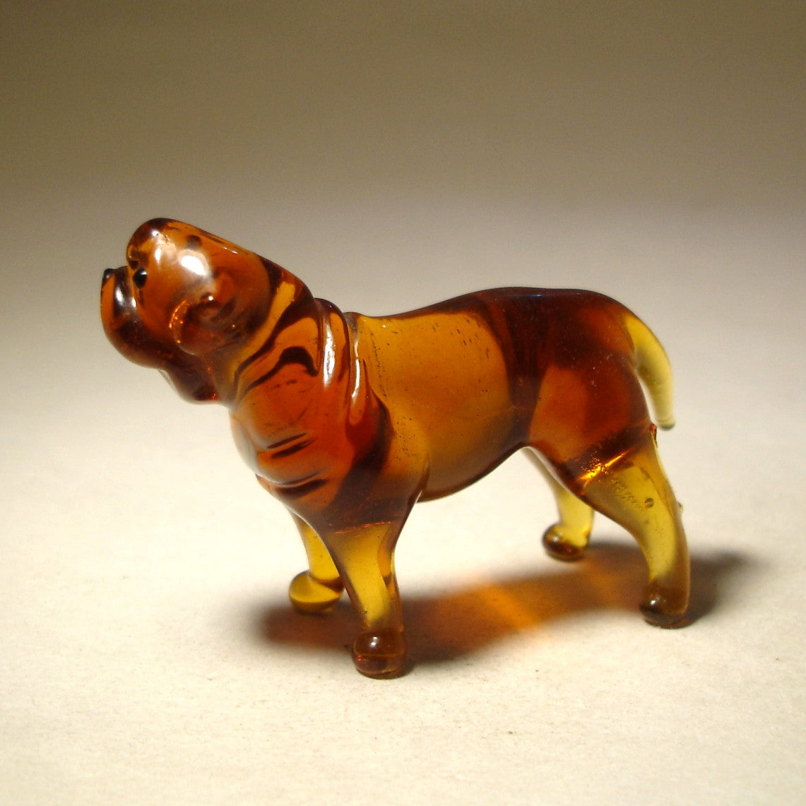 The glass Mastiff figurine from a side view, emphasizing its strong stance and the elegant curves of its body.