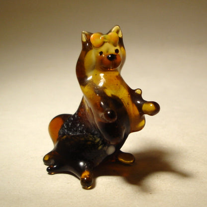 The glass Pekingese figurine from a side angle, displaying its regal posture and the graceful flow of its tail.