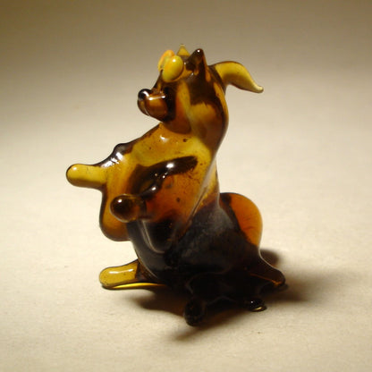 A close-up view of the glass Pekingese figurine, highlighting its face and flowing fur on its head.