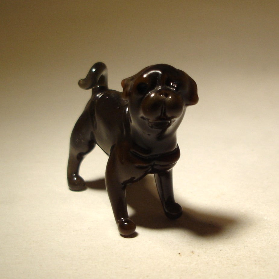 Close-up of the glass Black Pug figurine's face, capturing its big, expressive eyes and charming personality