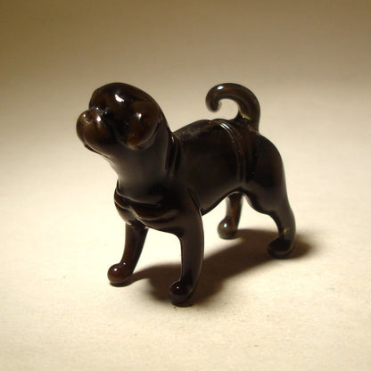 Side view of the glass Black Pug figurine, highlighting its curly tail and playful stance,