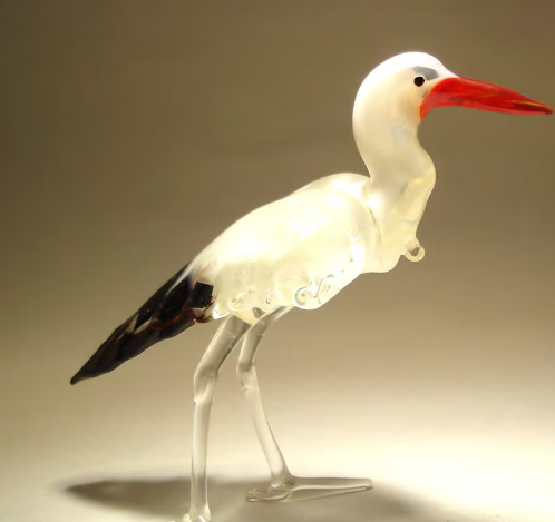 A front view of a glass stork egret figurine, showcasing its elegant long neck, slender legs, and detailed red beak.