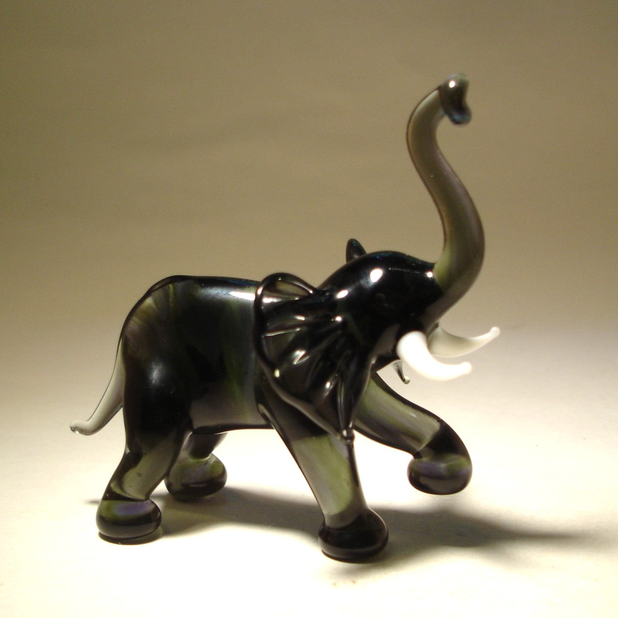 Handmade dark grey glass elephant figurine standing with its foot high.