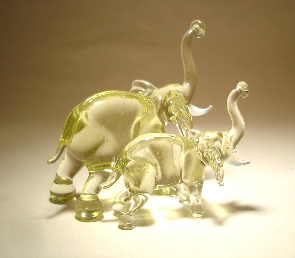 The glass elephant and baby figurines are displayed from the side, emphasizing the baby elephant standing close to the larger one.