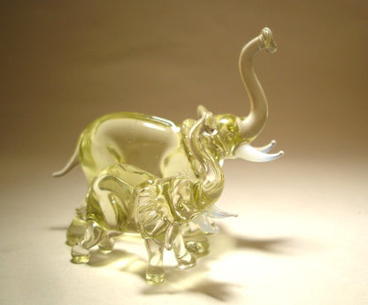 A handcrafted glass elephant figurine with a baby elephant beside it in ight beige color.