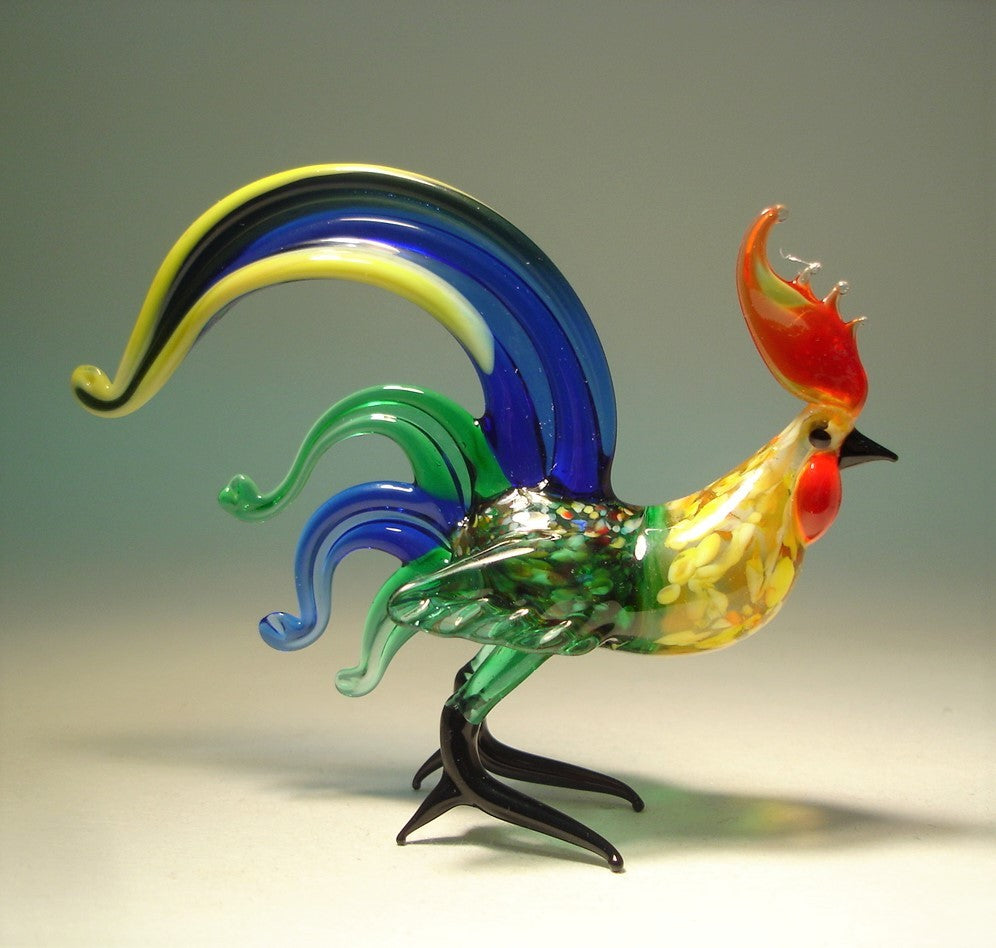 Right side view of the glass blue fighter rooster figurine, focusing on the craftsmanship of its comb, feathers, and fierce expression. 