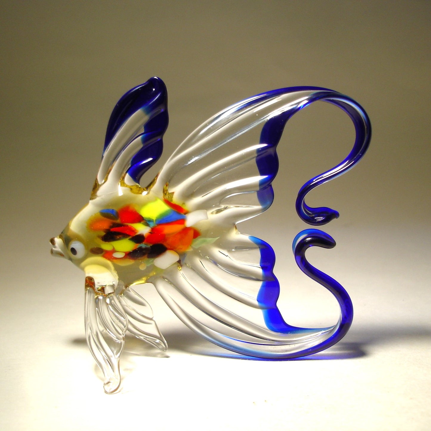 Side view of the blue and clear glass fish figurine, highlighting the arched tail trimmed in cobalt blue