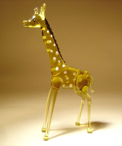 A side view of a glass standing giraffe figurine, highlighting its elegant posture and unique spotted design.