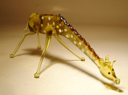 Front view of a glass giraffe figurine bending down to drink water, showcasing its long neck and intricate body details
