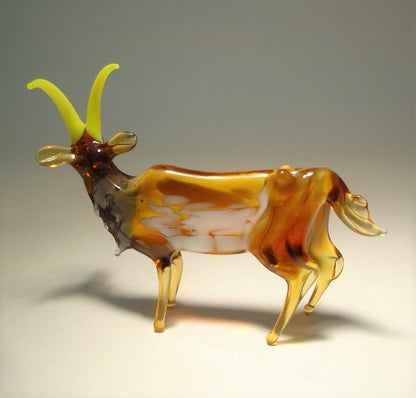 A close-up of the glass goat figurine's texture, focusing on the spotted in white brown body and the delicate details of its tail.