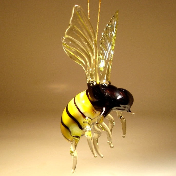 Side view of a glass bee ornament, highlighting its delicate wings and fine details while suspended for hanging.