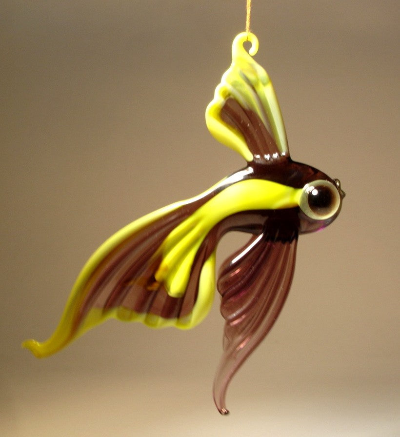 A close-up shot of the hanging glass telescope fish ornament, suspended from a thread, focusing on the large, expressive eyes.