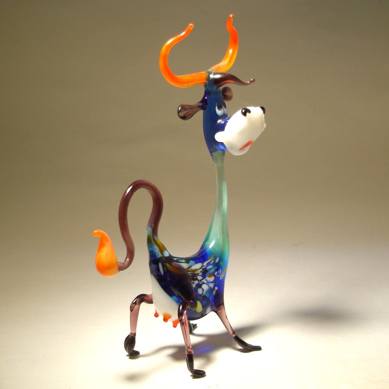 Rear view of the Glass Happy Cow Figurine, emphasizing the curled tail and the long neck.