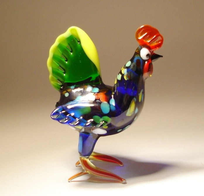 Front view of a glass colorful hen figurine, showcasing its vibrant plumage in shades of cobalt blue, yellow, and green.