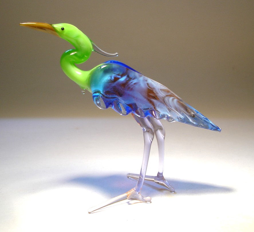 A side view of the glass Green Neck Heron figurine, emphasizing its slender body and long legs.