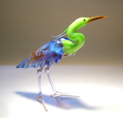 A graceful glass Green Neck Heron figurine standing elegantly with its long neck extended, showcasing detailed feathers in various shades of blue.