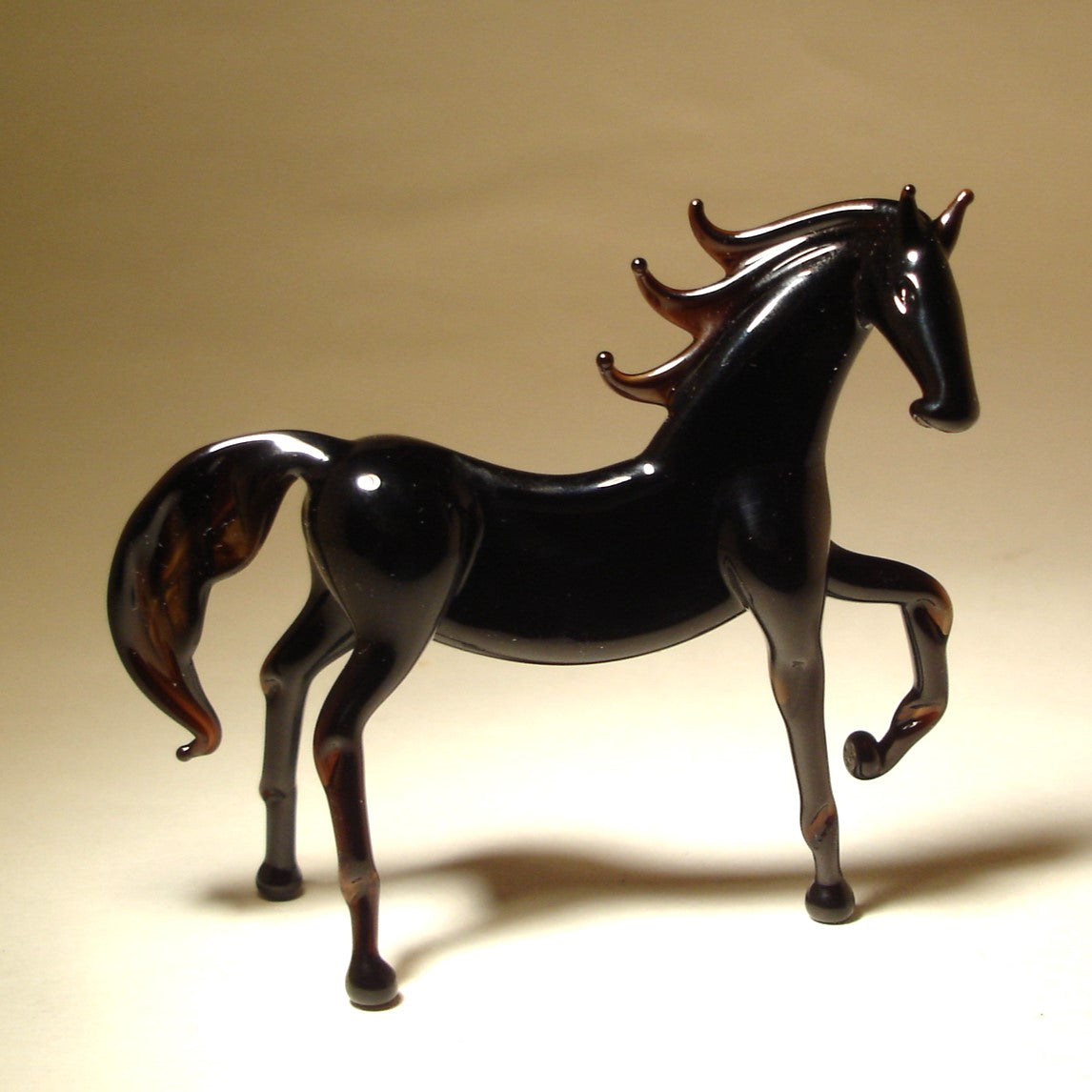 Side view of the Glass Black Horse Figurine, highlighting the raised front leg and detailed muscular body.