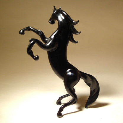 A left side view of the handmade black rearing horse figurine.