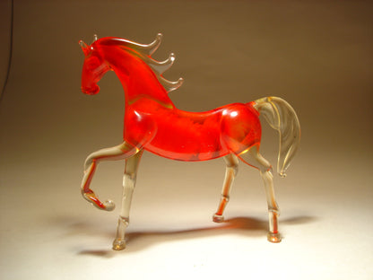 A back view of a red glass horse figurine, featuring its raised left foot, arched neck, and a flowing mane.