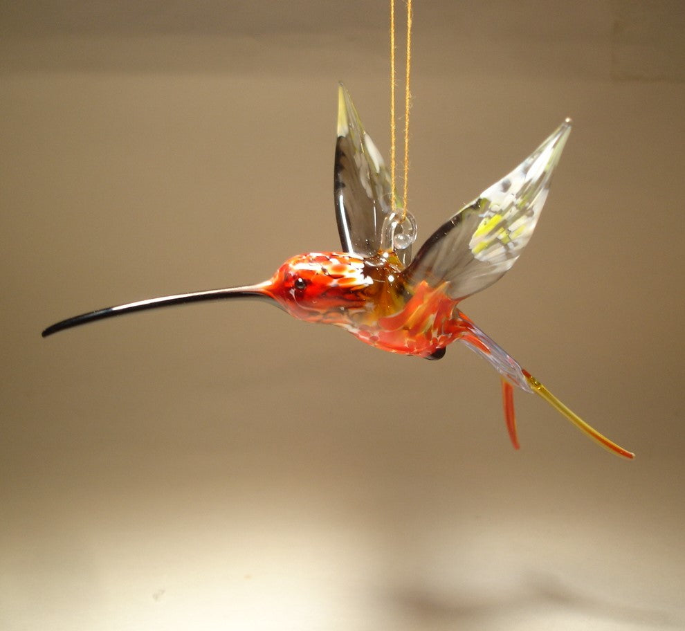 Left side view of the suspended in air hummingbird showcasing a transparent grey wins with white and yellow specs.