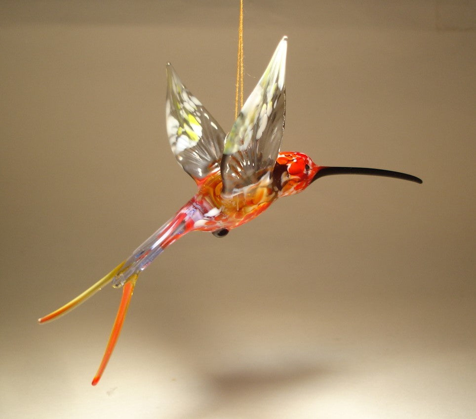 Side view of a glass red and grey swallowtail hummingbird ornament suspended from a thread.