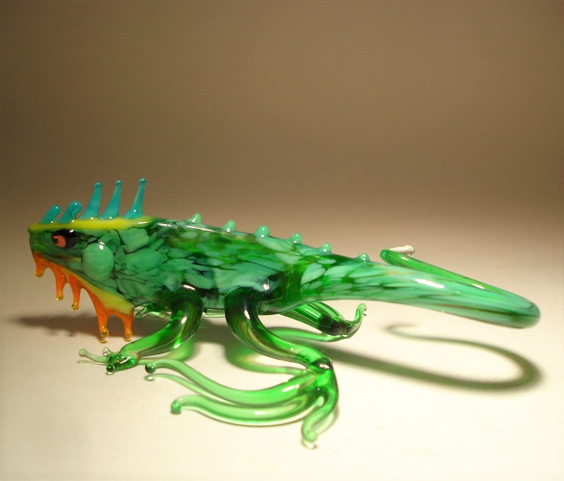 A glass green iguana figurine with intricate hind leg curved fingers.