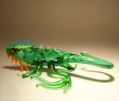 A glass green iguana figurine with intricate hind leg curved fingers.