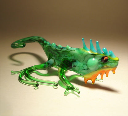 A detailed glass figurine of a green iguana, showcasing its textured skin and vibrant green color.