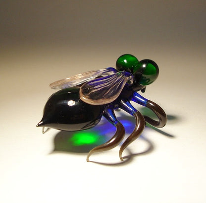 A close-up shot of the glass Green-Eyed Fly figurine, focusing on the finely crafted legs and clear glass wings.